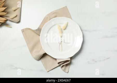 Elegant plate with spikes and napkin on white marble table, top view Stock Photo