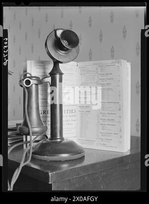 Old-fashioned telephone with printed telephone directory on wooden stand, Dubuque, Iowa, April 1940.  (Photo by John Vachon/Office of War Information) Stock Photo