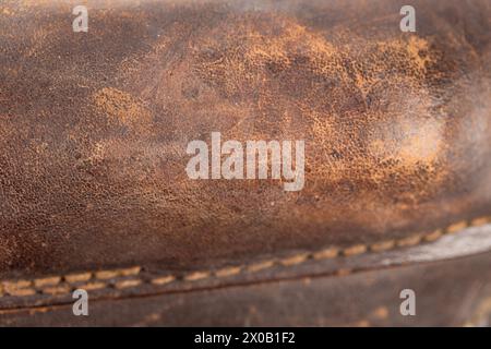 Old brown leather with a sewn seam. It occupies the entire surface of the image. Close-up. Stock Photo
