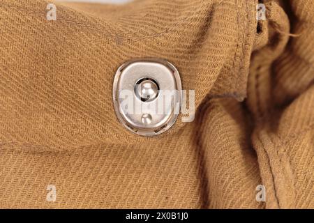 A fragment with a rivet from an old duffel. It is occpies the entire surface of the image. Close-up. Stock Photo