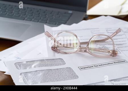 Chappaqua, NY - 9, April 2024: Laptop, reading glasses with documents, income tax forms and envelope on top that says Important Tax Information. Stock Photo