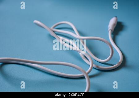 White folded usb and micro usb cable on blue background. Stock Photo