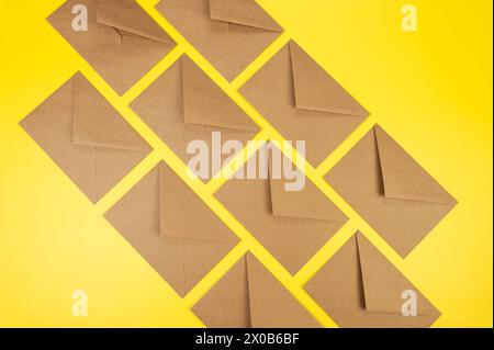 Top view of brown kraft envelopes on yellow background. Post flat lay. Copy space. Stock Photo