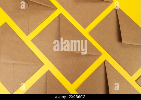 Top view of brown kraft envelopes on yellow background. Post flat lay. Copy space. Stock Photo