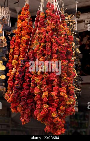 Colorful red-orange chili peppers hung on a strung for sale at an outdoor bazaar Stock Photo