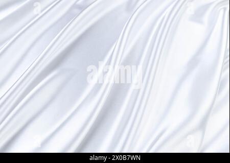 Luxury white satin background. Soft and elegant silk fabric. Flowing waves textile. Top view. Stock Photo