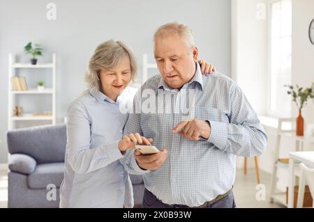 Elderly Family Couple Using Phone Together At Home Stock Photo