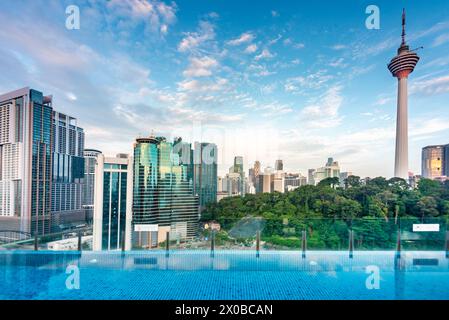 Stunning rootop view of KL city and Menara Kuala Lumpur,close to sunset with blue rooftop bar infinity pool in the foreground and blue sky dotted with Stock Photo