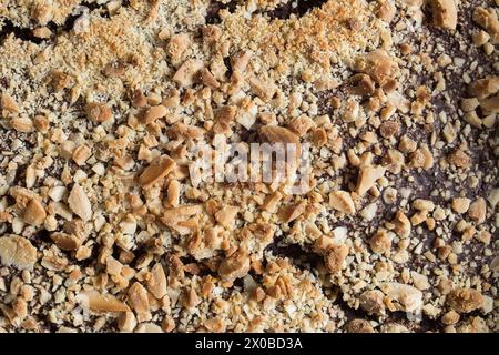 Close-up capture of crushed nuts and grains, featuring a rich tapestry of textures from light beige to dark brown.  Abstract organic background. Stock Photo