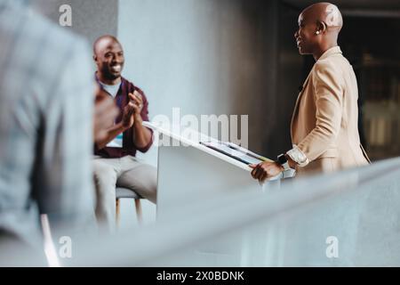 Professional engagement in a modern office setting, capturing a cheerful interaction between colleagues. A smiling woman in a business suit converses Stock Photo