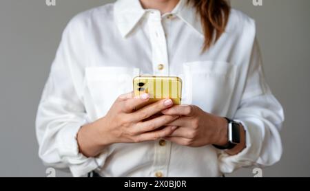 Businesswoman messaging online using her smartphone. Mobile phone in hands. Stock Photo
