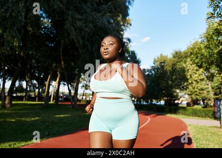 A curvy African American woman confidently exercises outdoors in a blue sports bra top and shorts. Stock Photo