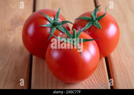 A group of red bunch tomatoes on a wooden table Stock Photo