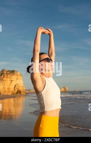 Woman finding inner peace and stretching in the sun on a beach. Stock Photo