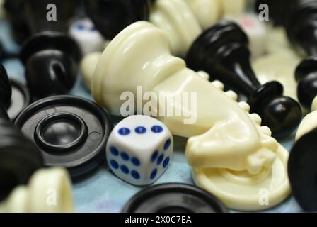 Close-up of chess pieces, a white horse, as well as playing chips and dice lie mixed on the table Stock Photo