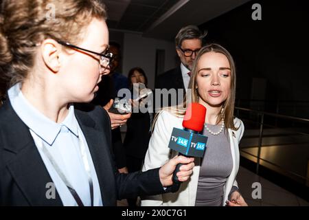 Confident female US politician answers press questions and gives interview for media walking in corridor of government building. American delegation surrounded by crowd of journalists. Press campaign. Stock Photo