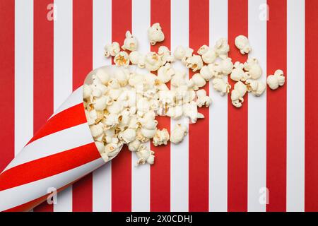 Flat lay composition with popcorn on red and white stripes background. Stock Photo