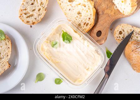 Homemade Vegan Butter, non-dairy creamy, plant based alternative butter with soy bean leave, and home baked bread on kitchen white table background Stock Photo