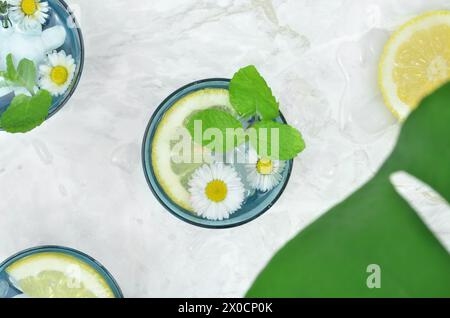 Three drinks in blue glasses decorated with mint, lemons and flowers. Top view. Summertime. Stock Photo