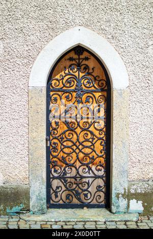 A small wooden door with a forged metal grille in the wall of the abbey. Stock Photo