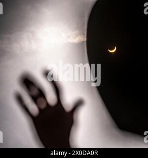 Hand reaching up to touch a total solar eclipse Stock Photo
