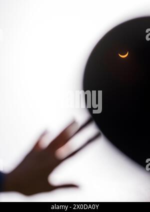Hand reaching up to touch a total solar eclipse Stock Photo