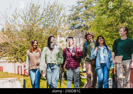 A diverse group of university students enjoy a sunny day on campus - friends walking and laughing together, sharing a moment of genuine friendship and Stock Photo