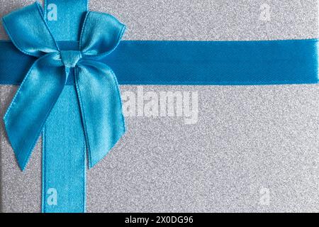 Gift box with blue satin ribbon and bow on grey background Stock Photo