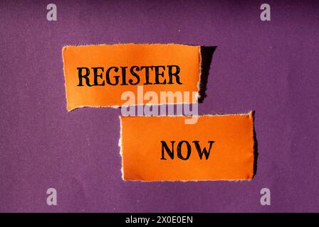 Register now words written on ripped orange paper pieces with purple background. Conceptual symbol. Copy space. Stock Photo