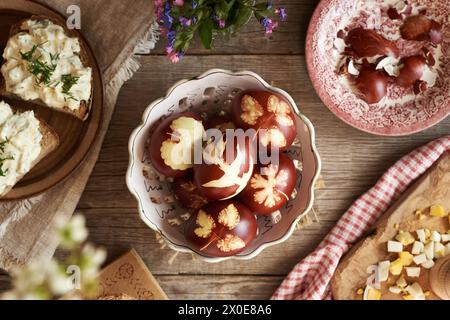 Brown Easter eggs dyed with onion peels, with slices of sourdough bread with spread made of hard-boiled eggs on a wooden table Stock Photo