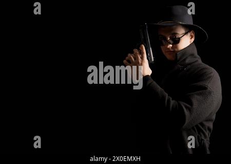 Male spy with gun on black background Stock Photo