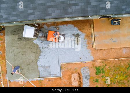 Pouring fresh cement from concrete buggy into framework in ground during construction Stock Photo