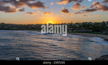 The sun sets over Shipwreck Beach and the Grand Hyatt Kauai Resort and Spa on the island of Kauai, Hawaii, USA. Stock Photo