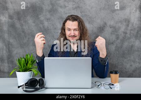 A stylish young man poses in a studio against a grey background ...