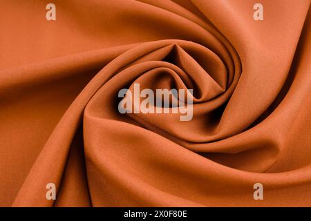 Close up abstract textile background of dark brown folded pleats of fabric, directly above. Stock Photo