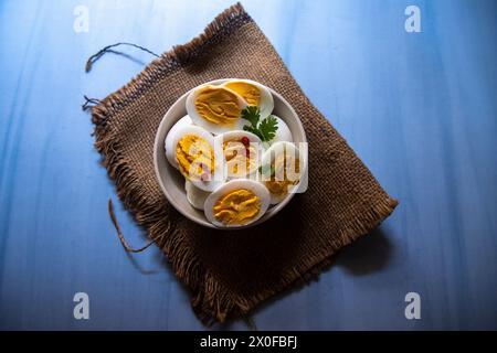 Sliced boiled eggs in a bowl with parsley leaves. Stock Photo