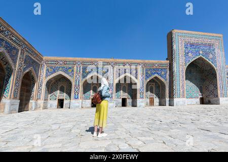 Happy attractive woman tourist in hat, posing at the entrance in Registan square Samarkand, Uzbekistan Stock Photo