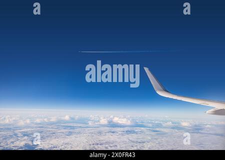 Airplane flying over clouds during on a sunny day Stock Photo