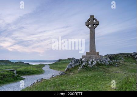 A Celtic cross on Llanddwyn, along the coast of Anglesey, Wales, near Newborough Beach. It is sunset Stock Photo