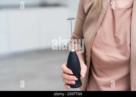 The hand holds a cappuccino mixer. Close up. Isolated on a white background. Stock Photo