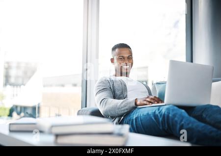Man, portrait and remote work with laptop in home office on sofa with online research and writing code. Email, communication and happy web developer Stock Photo