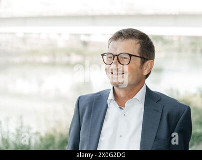 Confident smiling man in a blue suit by a tranquil river Stock Photo