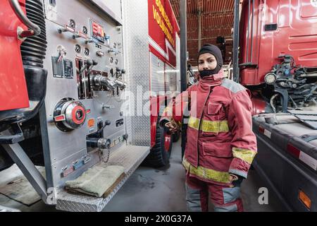 Female Firefighter In Fire Protection Suit standing at fire station Stock Photo