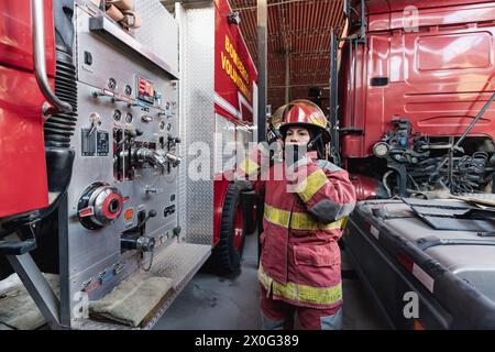 Female Firefighter In Fire Protection Suit standing at fire station Stock Photo