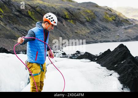 Young man in colourful clothes swings a rope on an Icelandic glacer Stock Photo