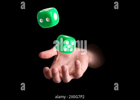Man throwing green dice on black background, closeup Stock Photo