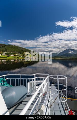 Ferry deck with a view of the tranquil waters and mountains around the village Kvanne on the Stangvikfjord, blue sky white clouds in Norway Stock Photo