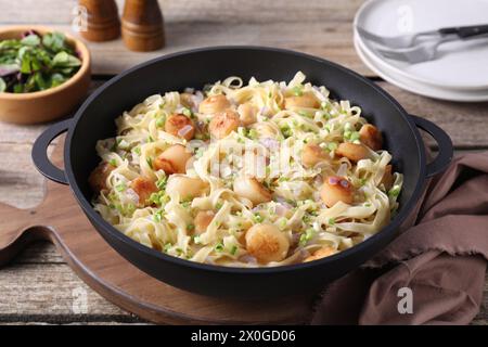 Delicious scallop pasta with onion in pan on table, closeup Stock Photo