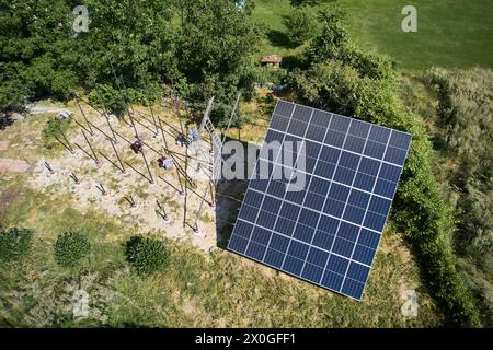 Workers installing solar panels in field at sunny day. Array as a system of photo-voltaic panels. Arrays of a solar panel system supplying solar electricity to electrical equipment. Stock Photo