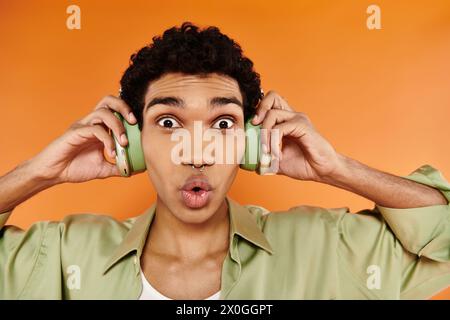 surprised appealing african american man in trendy attire with headphones and smiling at camera Stock Photo